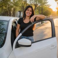 Mujer junto a su auto en una calle arbolada